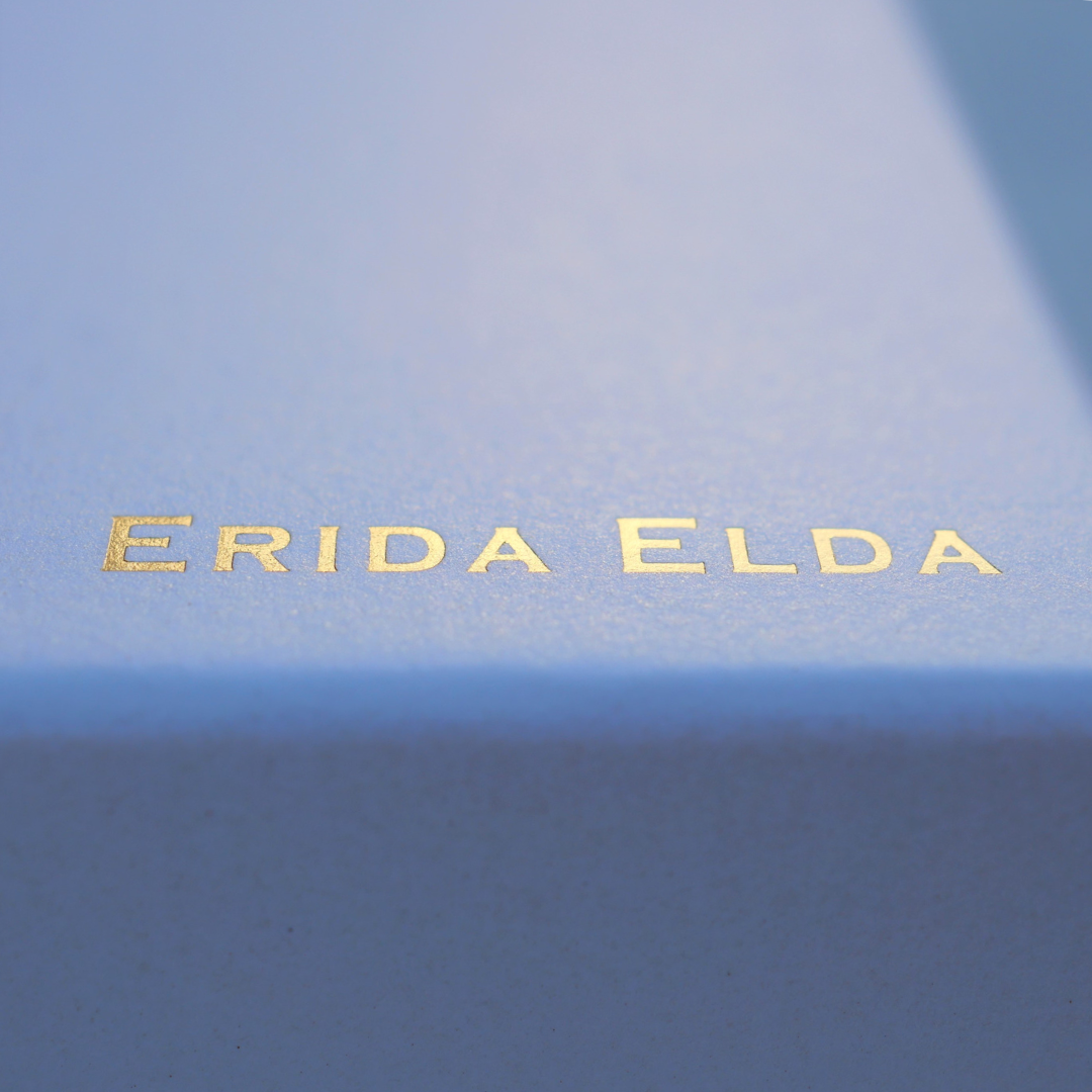 淡いブルーのジュエリーボックスに刻印された、ゴールドの「ERIDA ELDA」ロゴ。上質で静かな輝きを持つブランドパッケージ。