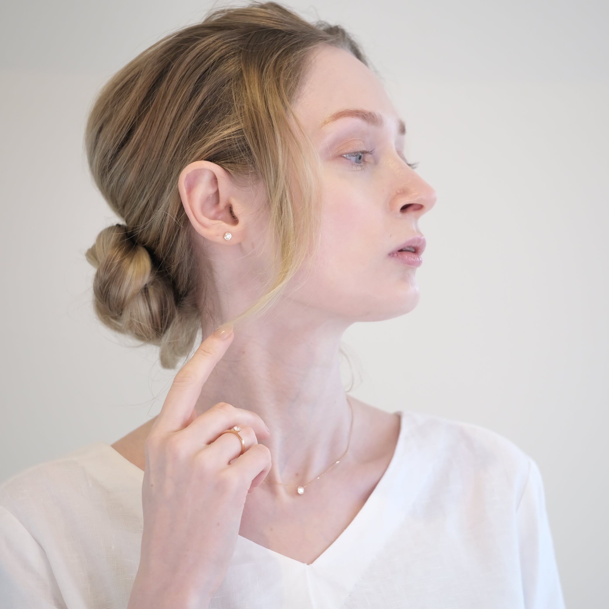 白い服にローズゴールドの指輪・ネックレス・ピアスを身につけた外国人モデルの上品なコーディネート