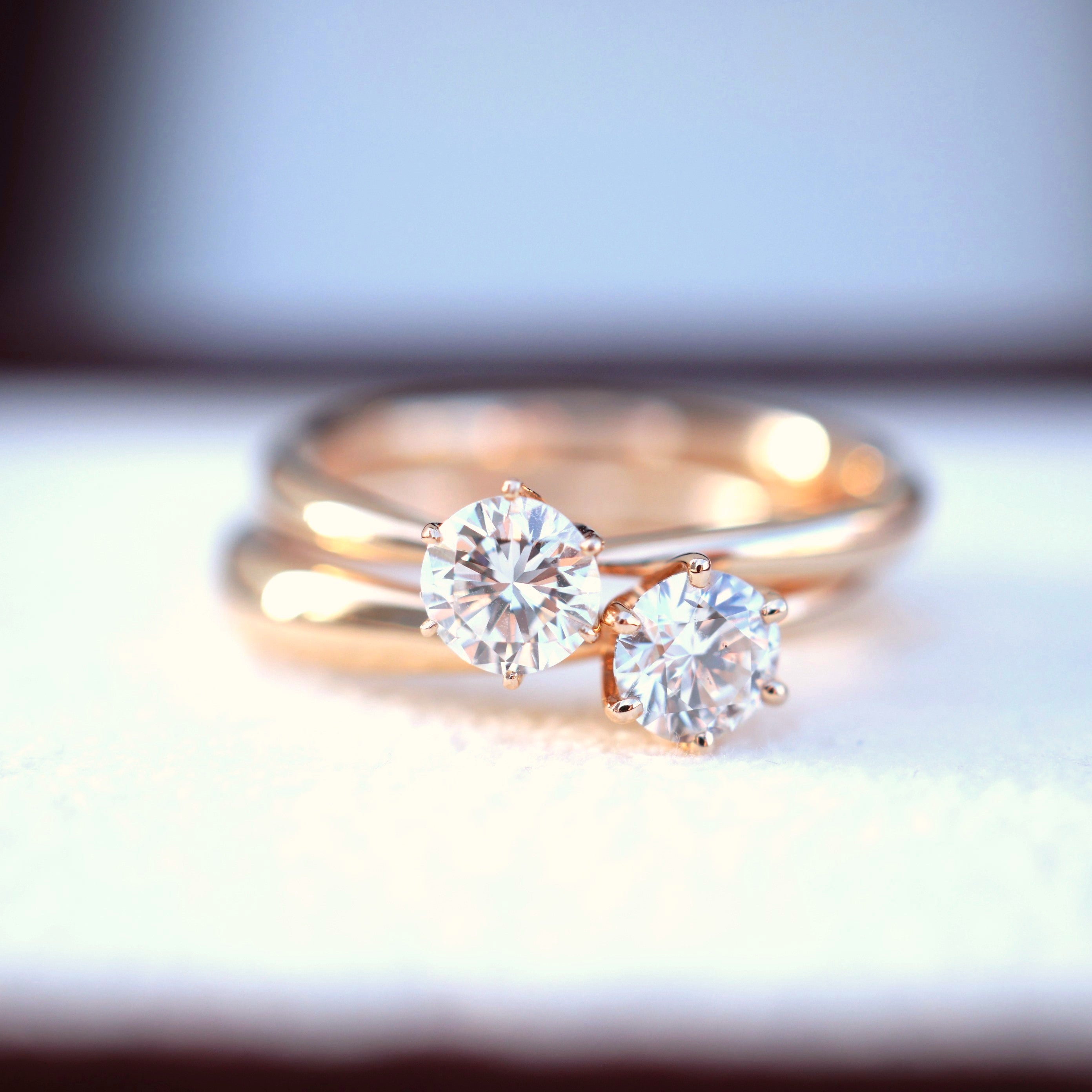 ローズゴールドの一粒ダイヤリングを2本並べた写真。0.3カラット前後の天然ダイヤモンドが光を受けて強く輝くシンプルデザインのソリティアリング。